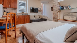 Un espacio habitable compacto con kitchenette, comedor, sofá, cama y pared de ladrillo.