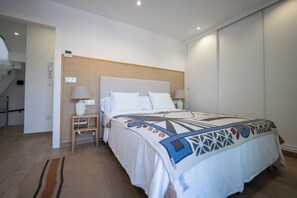 Une chambre d’hôtel avec un lit, des tables de chevet, une lampe, un téléphone fixé au mur et une porte.