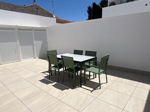 A patio with a table and chairs, a white wall, and a tiled floor. - House with large swimming pool 1 minute 30 walk from the beach (Santiago de la Ribera)