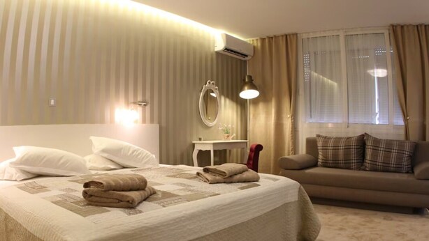 Ein Hotelzimmer mit einem großen Bett, einer Couch, einem Spiegel und einer Klimaanlage.