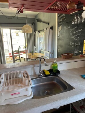 A kitchen with a sink, a chalkboard with writing, and a dining area with chairs and a table.