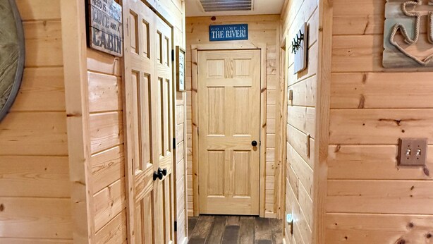A wooden cabin interior with a central door, wooden walls, and a sign above the door. - Lakeside Cabin at Deer Run by Stay Current River (Van Buren)