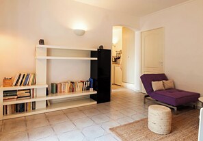 Uma sala de estar moderna com um sofá, uma estante e uma pequena mesa.