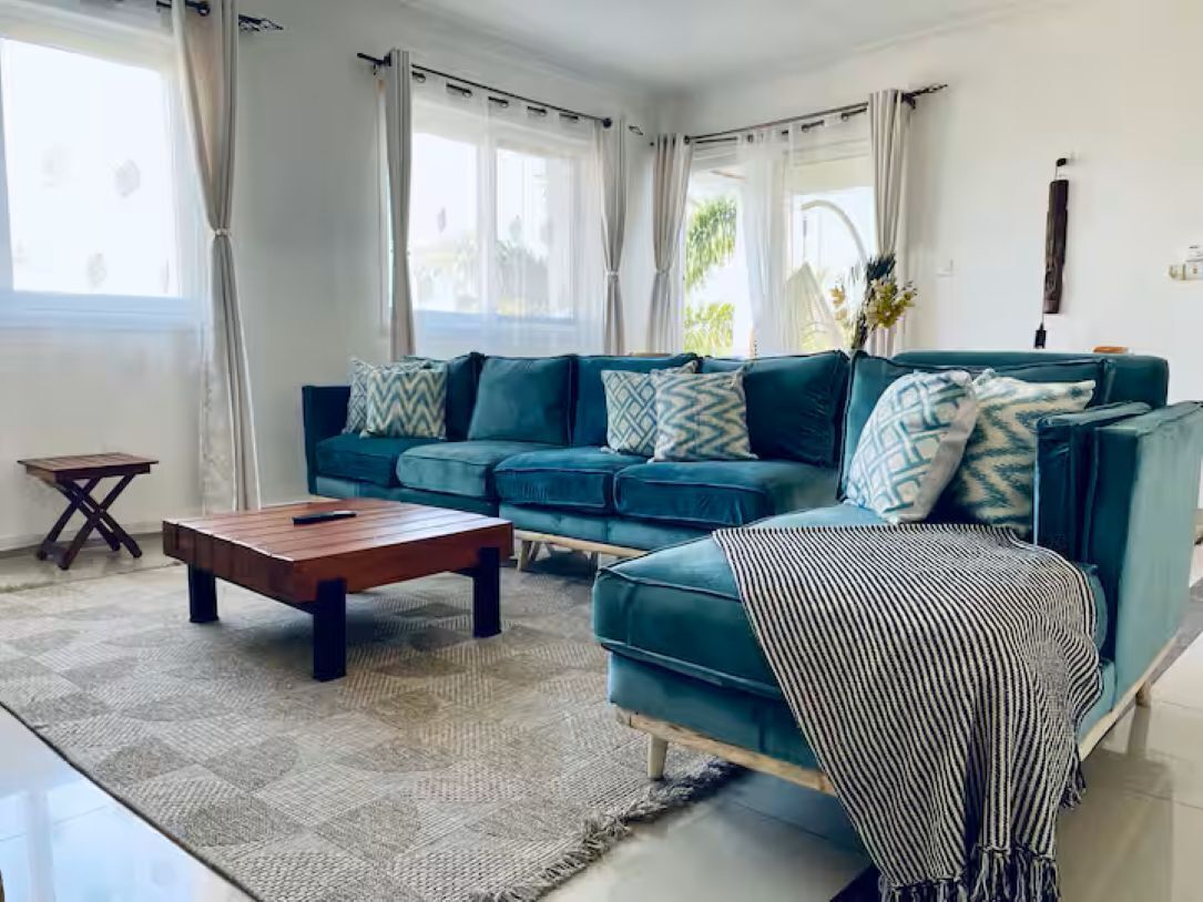 Un salon avec un canapé de couleur turquoise, une table basse en bois et un plaid à rayures.
