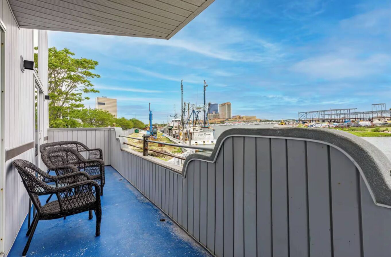 A balcony with wicker chairs, a view of a construction site, and a clear blue sky.