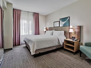 A hotel room with a bed, a nightstand, a lamp, and a chair.