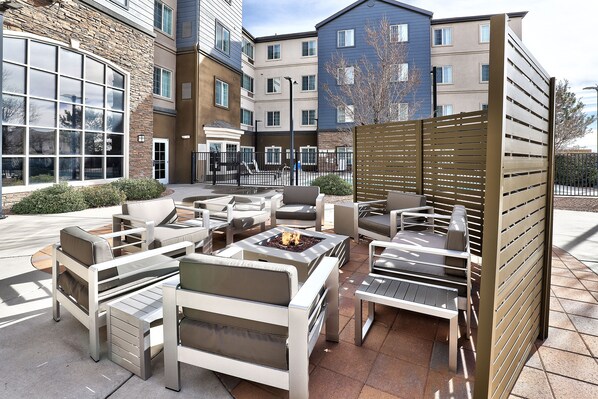 An outdoor seating area with multiple lounge chairs and a fire pit.