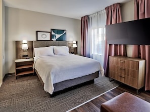Una habitación de hotel con cama, mesitas de noche, televisor y un armario de madera.