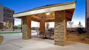 A covered patio with stone pillars, outdoor furniture, and a grill area. - Cozy Studio w/ Free Breakfast, Pool & BBQ Area (Albuquerque)