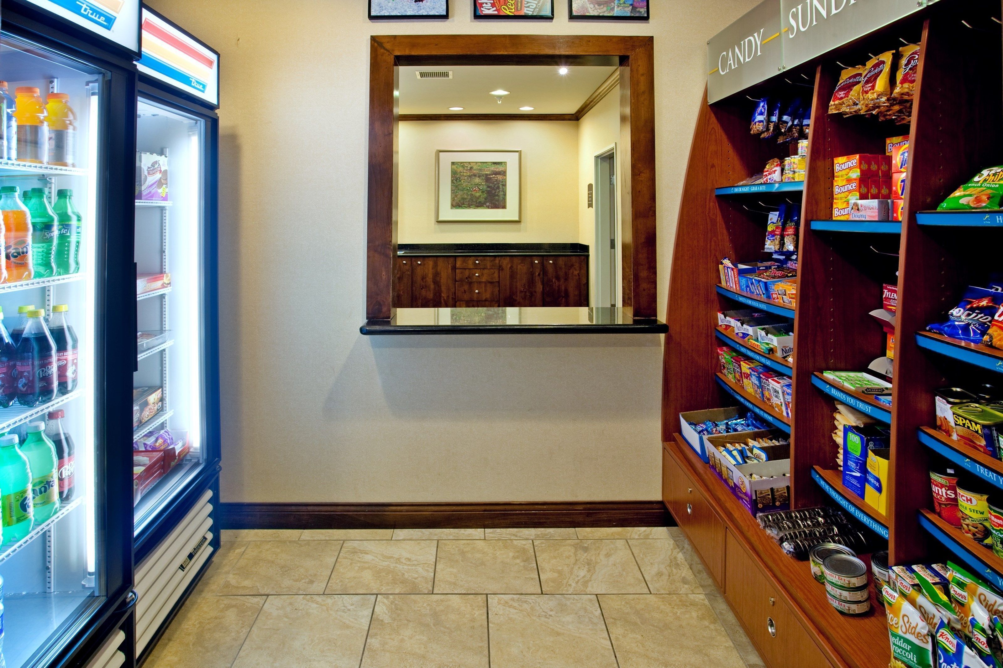 A hotel lobby with a vending machine, a candy shelf, and a framed artwork on the wall.