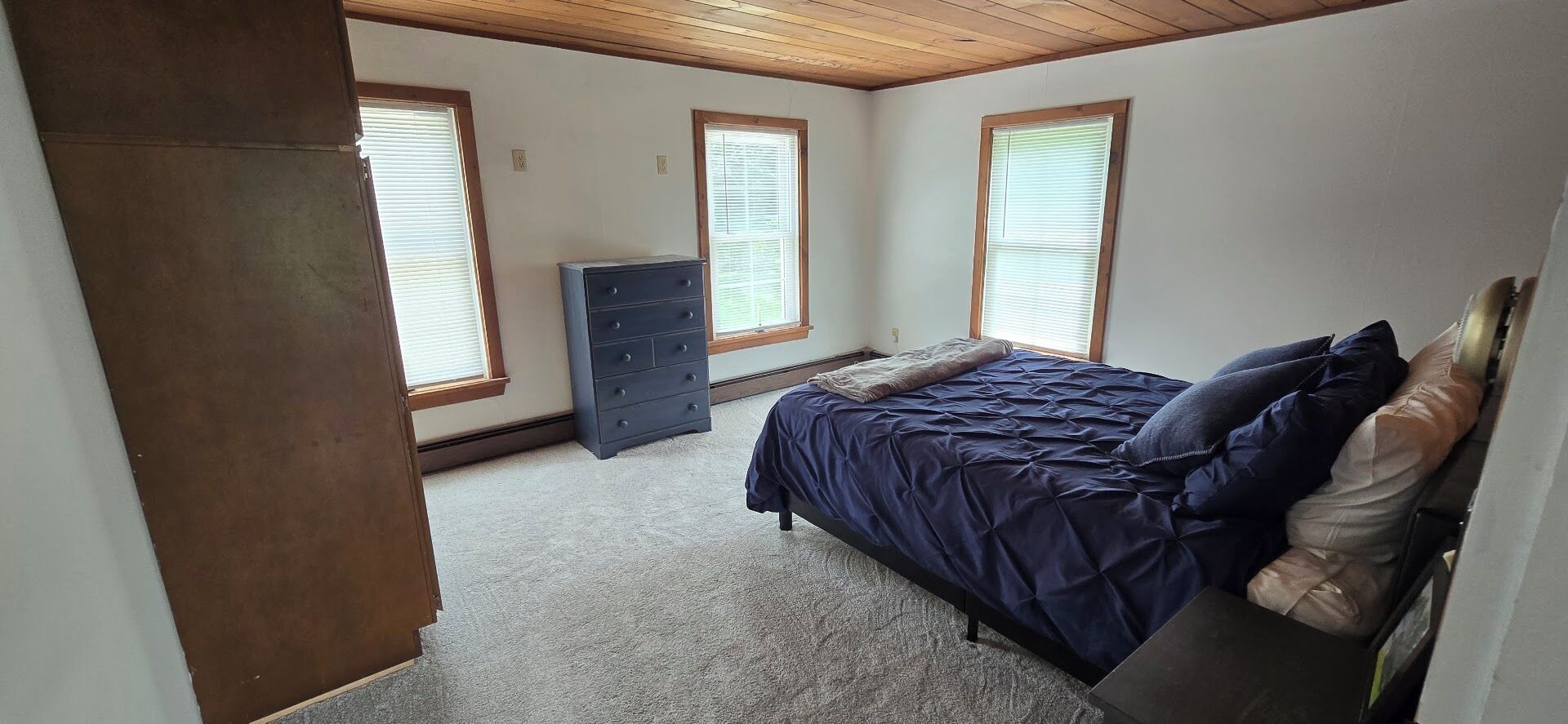 Een slaapkamer met een bed, een dressoir en ramen.