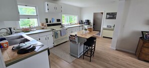 A modern kitchen with white cabinets, a central island, a coffee maker, and a view of the outdoors. - Enjoyable 3-bedroom house in charming Turin perfect for your stay (Turin)