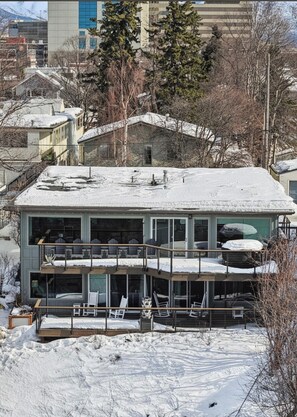 Ein zweistöckiges Haus mit Balkon, Garage und einem mit Schnee bedeckten Dach.