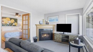 Ein Wohnzimmer mit Kamin, Fernseher, Sofa und einem Bild an der Wand.