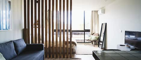 A modern living room with a sofa, a TV, a chair, and a wooden partition.