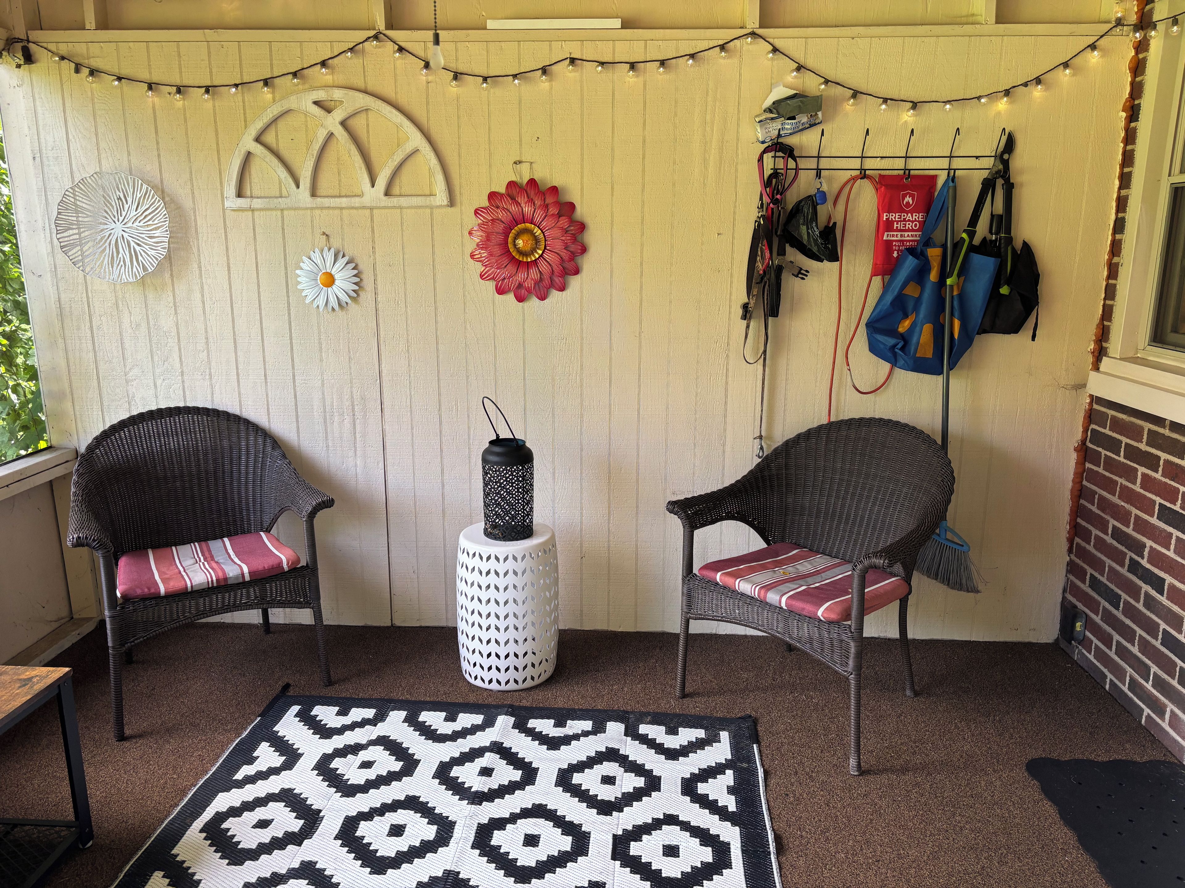 Un área de estar al aire libre acogedora con sillones de mimbre, un tapete estampado y adornos en la pared.