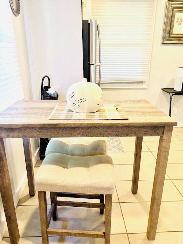 Una mesa de comedor con un centro de mesa de calabaza, un banco y una ventana con persianas.