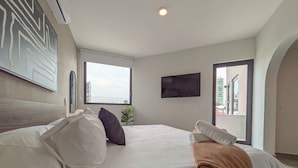 Camera da letto con un grande letto, una televisione a schermo piatto, una finestra e vista sulla città.