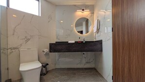 Un bagno con toilette, lavandino, specchio e pareti in marmo.