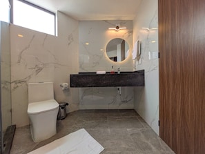 Ein Badezimmer mit Toilette, Waschbecken, Spiegel und Marmorwänden.