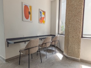 Una habitación moderna con una encimera negra, tres sillas y dos cuadros abstractos en la pared.