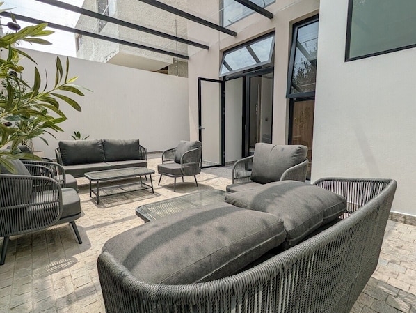 A modern outdoor seating area with wicker furniture and a glass ceiling. - Casa Heredia 1Bed Studio (Guadalajara)