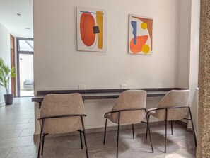 Un interior moderno con un mostrador de recepción, dos sillas y arte abstracto en la pared.