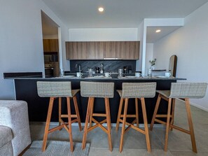 Een moderne keuken met een centraal eiland, een paar barkrukken en houten keukenkastjes.