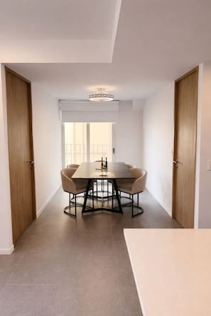 Een moderne eetruimte met een tafel, stoelen, een kroonluchter en houten deuren.