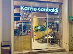 Una vetrina in vetro, un'insegna con la scritta 'Karne Garibaldi' e una scala che conduce a un piano superiore.