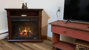 Ein Kamin mit Fernseher und Lowboard davor.