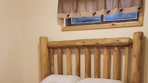 Ein hölzernes Bett mit Kopfteil, einer roten Bettdecke und einem gemusterten Teppich auf dem Boden.
