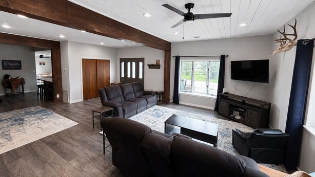 A spacious living room with a large sectional sofa, a ceiling fan, and a flat-screen TV mounted on the wall. - Charming Moore Home. Pet Friendly, Spacious & Comfortable for Families (Moore)