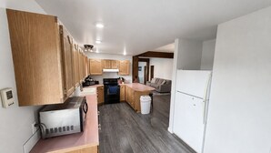 A modern kitchen with wooden cabinets, a built-in oven, a refrigerator, and a microwave. - Charming Moore Home. Pet Friendly, Spacious & Comfortable for Families (Moore)