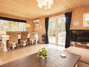 A wooden interior with a dining area, a TV, and a large window. - 4 Star Holiday Home in Blavand (Blavand)