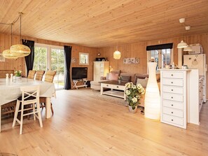 A wooden interior with a dining area, sofa, TV, and kitchen. - 4 Star Holiday Home in Blavand (Blavand)