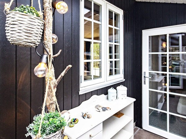 A rustic exterior with a white door, a window with multiple panes, a white shelf with jars, and a hanging light fixture. - 4 Star Holiday Home in Blavand (Blavand)