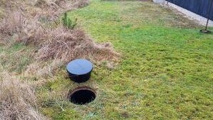 Un’area erbosa con un oggetto circolare e un buco nel terreno.