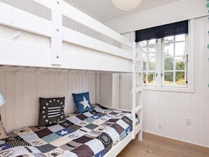 Ein Schlafraum mit Etagenbetten, einer gesteppten Bettdecke, einem Fenster mit Ausblick und weißen Holzwänden.