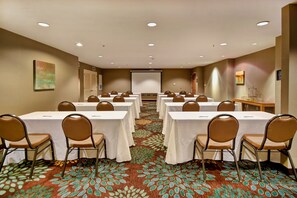 A conference room with multiple tables and chairs, a projector screen, and a carpeted floor. - Accessible 1BR Suite w/ Tub | Hot Breakfast + Pool (Madison)