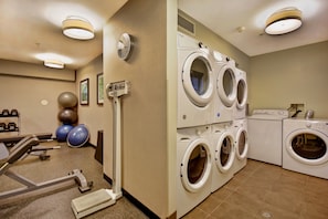 A gym with exercise equipment and a laundry area with multiple washing machines.