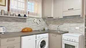 A compact kitchen with a washing machine, oven, and a sink. - SE273 – Senigallia, studio apartment near the sea (Senigallia)
