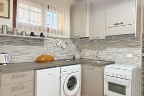 A compact kitchen with a washing machine, oven, and a sink. - SE273 – Senigallia, studio apartment near the sea (Senigallia)