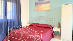A bedroom with a bed, a nightstand, a wardrobe, a painting, and a window with curtains. - SE273 – Senigallia, studio apartment near the sea (Senigallia)