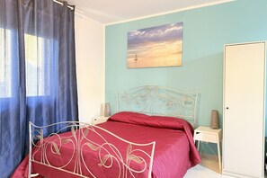 A bedroom with a bed, a nightstand, a wardrobe, a painting, and a window with curtains. - SE273 – Senigallia, studio apartment near the sea (Senigallia)
