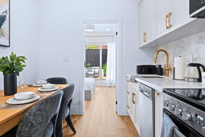 Una cocina moderna con armarios blancos, una estufa negra y un comedor con una mesa dispuesta para cuatro.