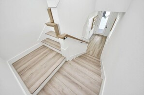 Una escalera con escalones de madera y paredes blancas.