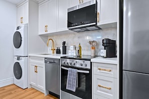 Una cocina moderna con armarios blancos, electrodomésticos de acero inoxidable y tiradores de madera.