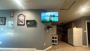 Una sala de estar con un televisor montado en la pared, un mueble bajo y una puerta.
