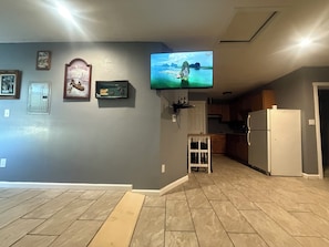 A living room with a television mounted on the wall, a small cabinet, and a door.
